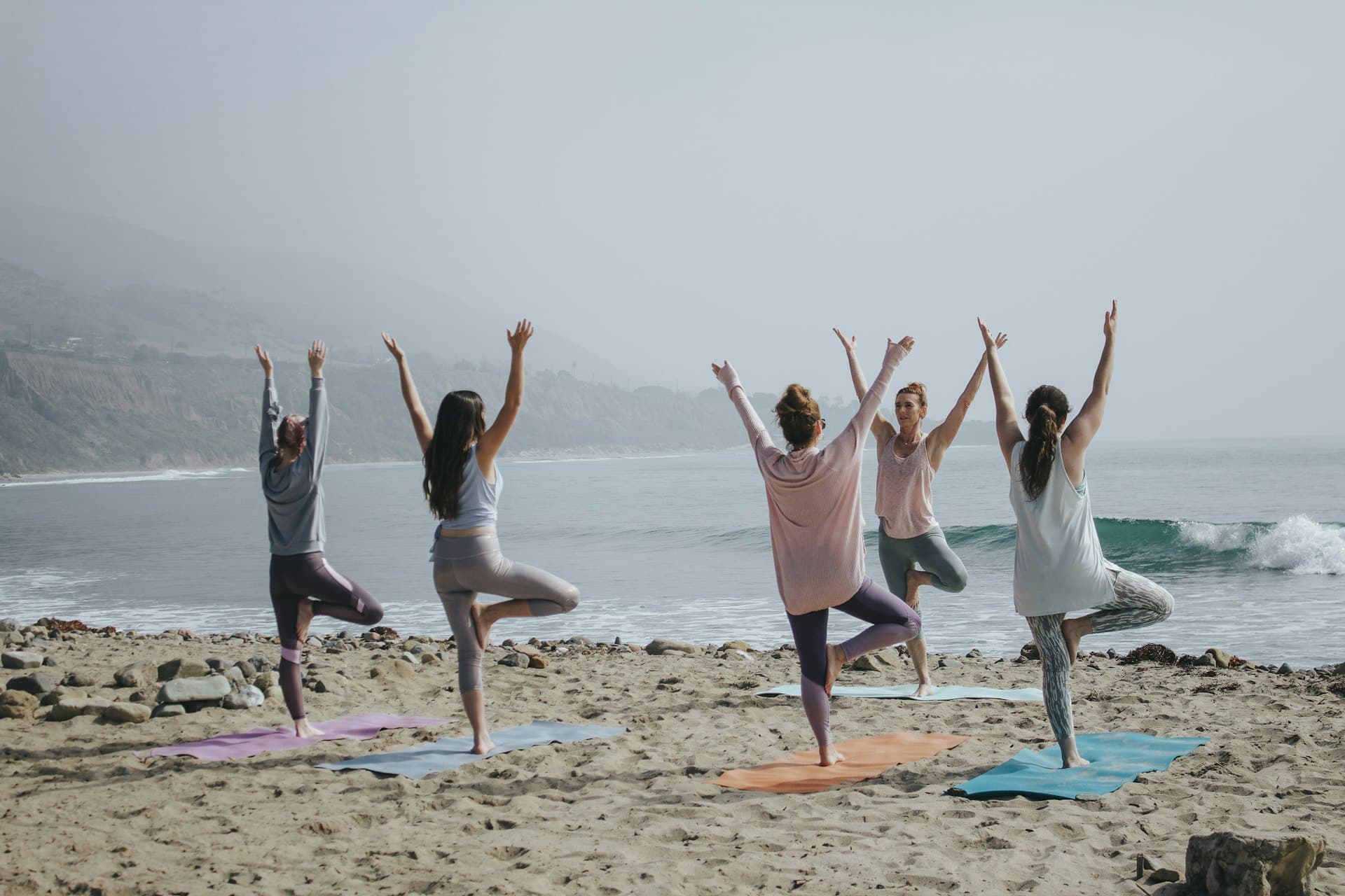 A person in a calm, naturally lit studio moving through a standing yoga pose